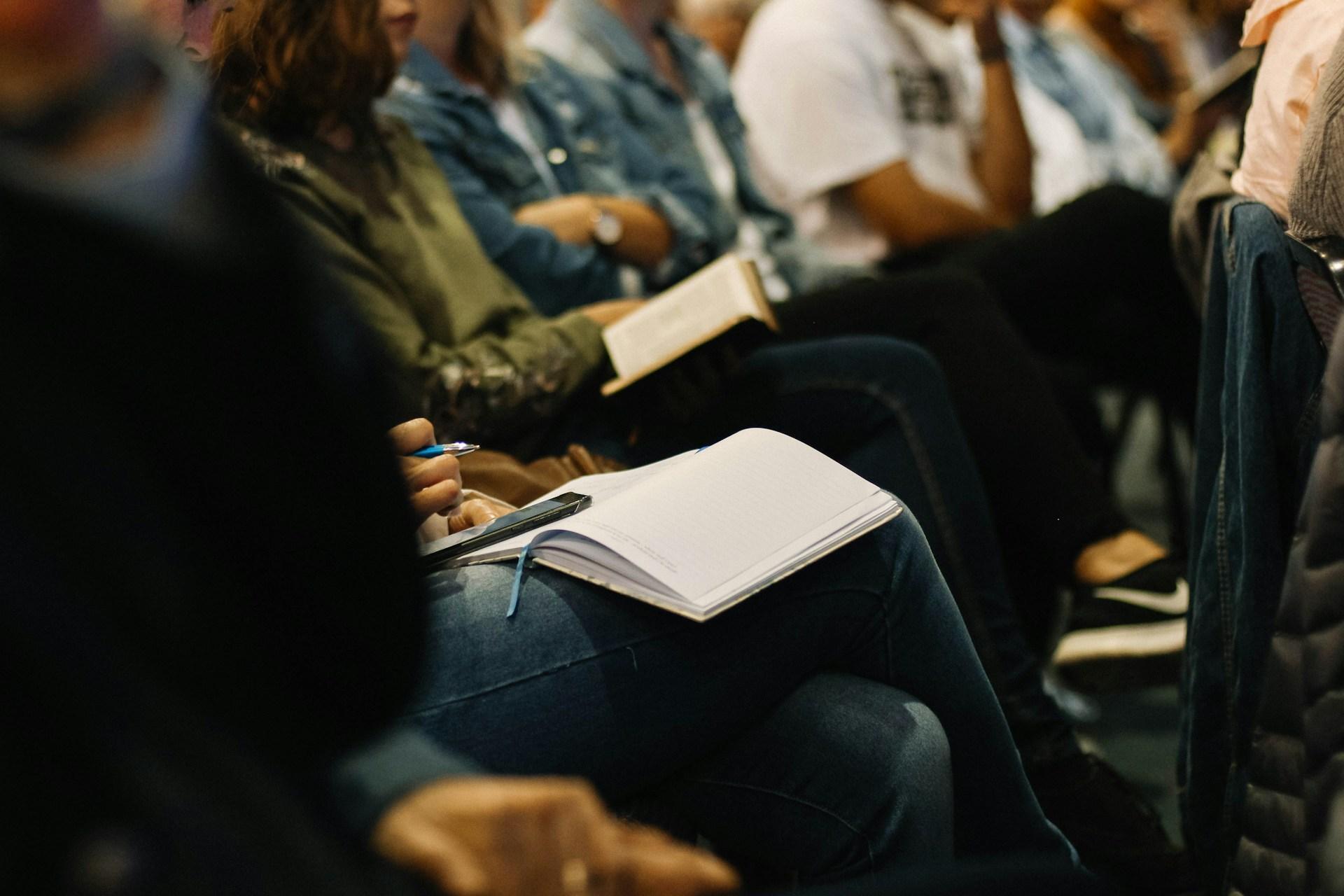 Attendee taking notes in a notebook during a conference session