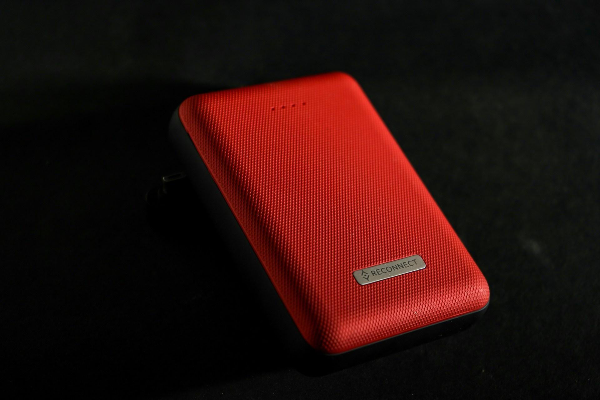 A red Reconnect power bank against an aesthetic deep black background