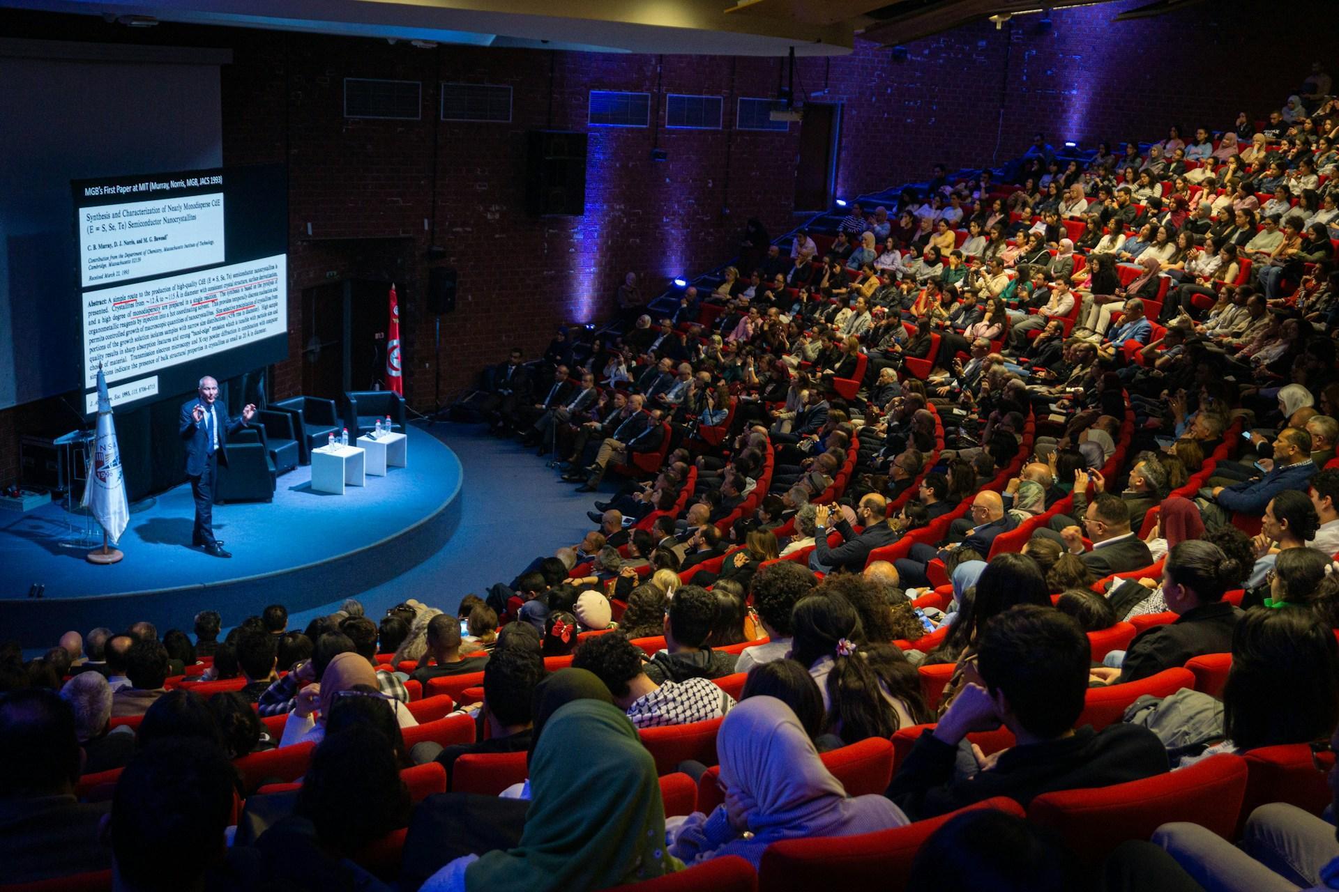 Speaker presenting to a packed auditorium at a professional conference event