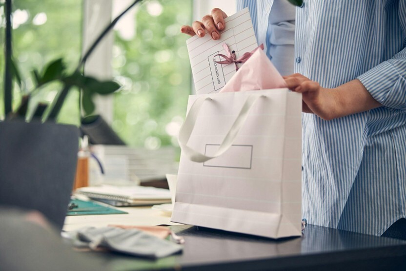 An unbranded gift bag being filled with a gift certificate