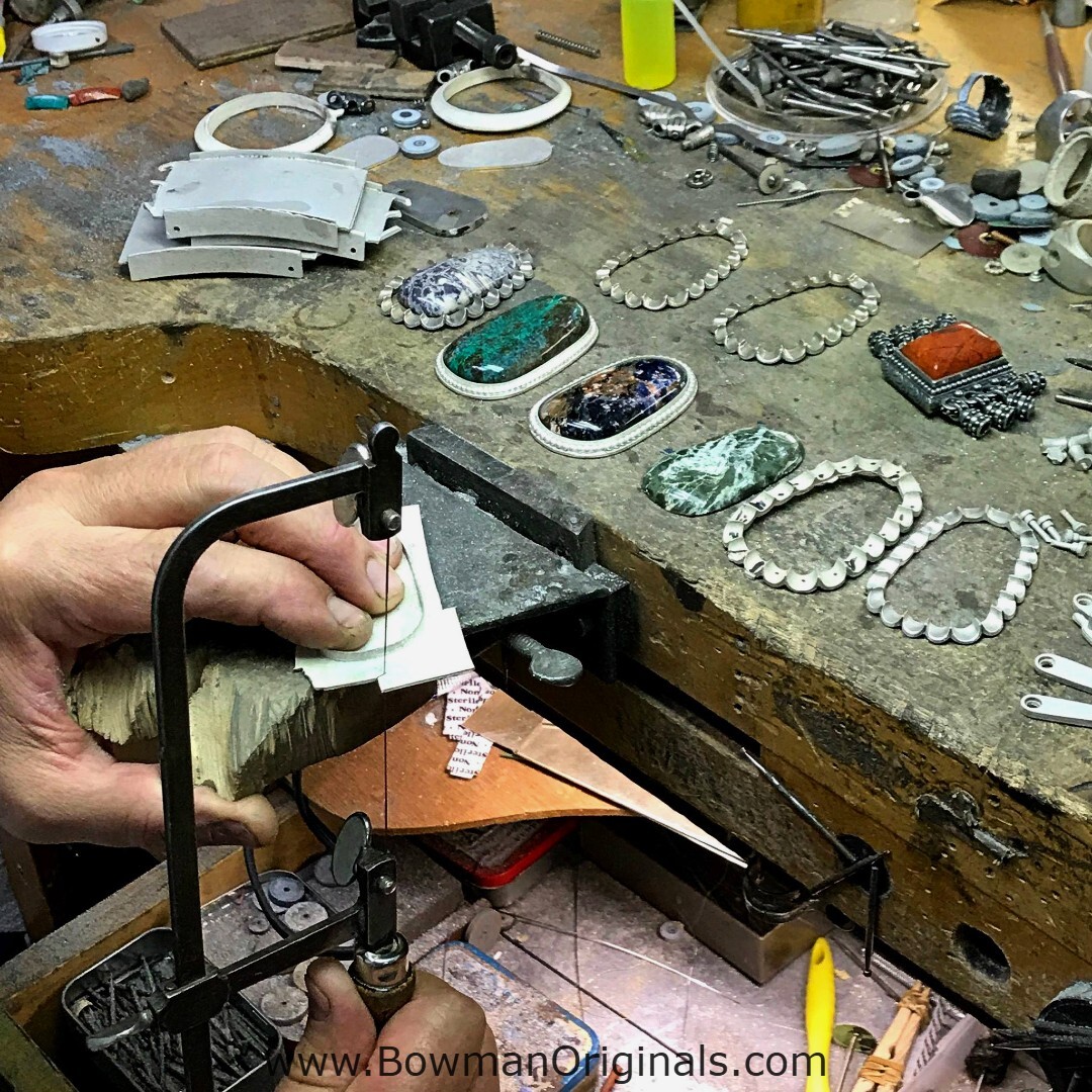 Jewelry designer Ned Bowman working on Handmade Sterling Silver Pendants on a jeweler's bench at Bowman Originals workshop.