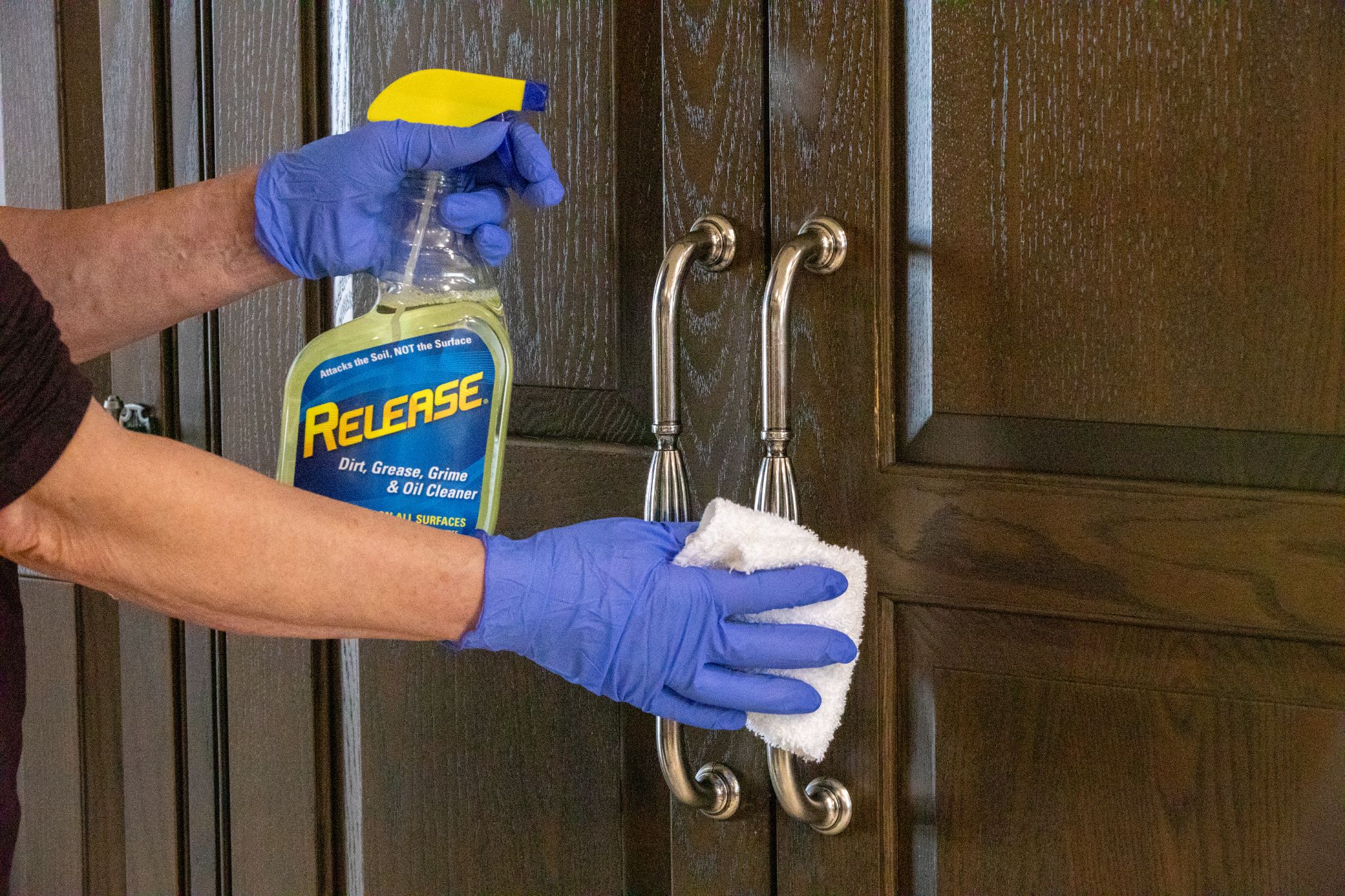 Applying a household cleaner to door handles.