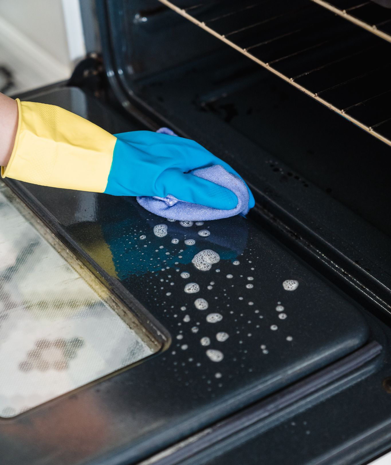 Person cleaning an oven with an all-purpose cleaner spray