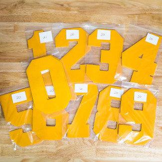Athletic Gold Jersey Numbers in bulk assortment on table