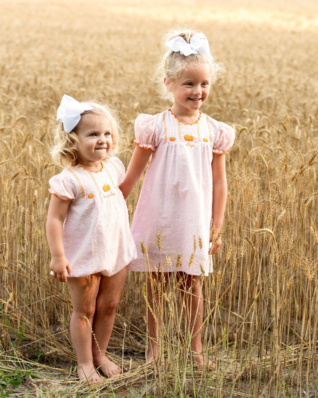 Two children dressed in adorable pumpkin-themed outfits from Cecil and Lou, perfect for fall pumpkin patch adventures.