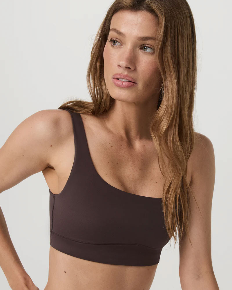 Vuori Women's AllTheForm Bra, close-up image of a woman wearing a black sports bra with a scoop neckline and wide straps, showcasing comfort and support.