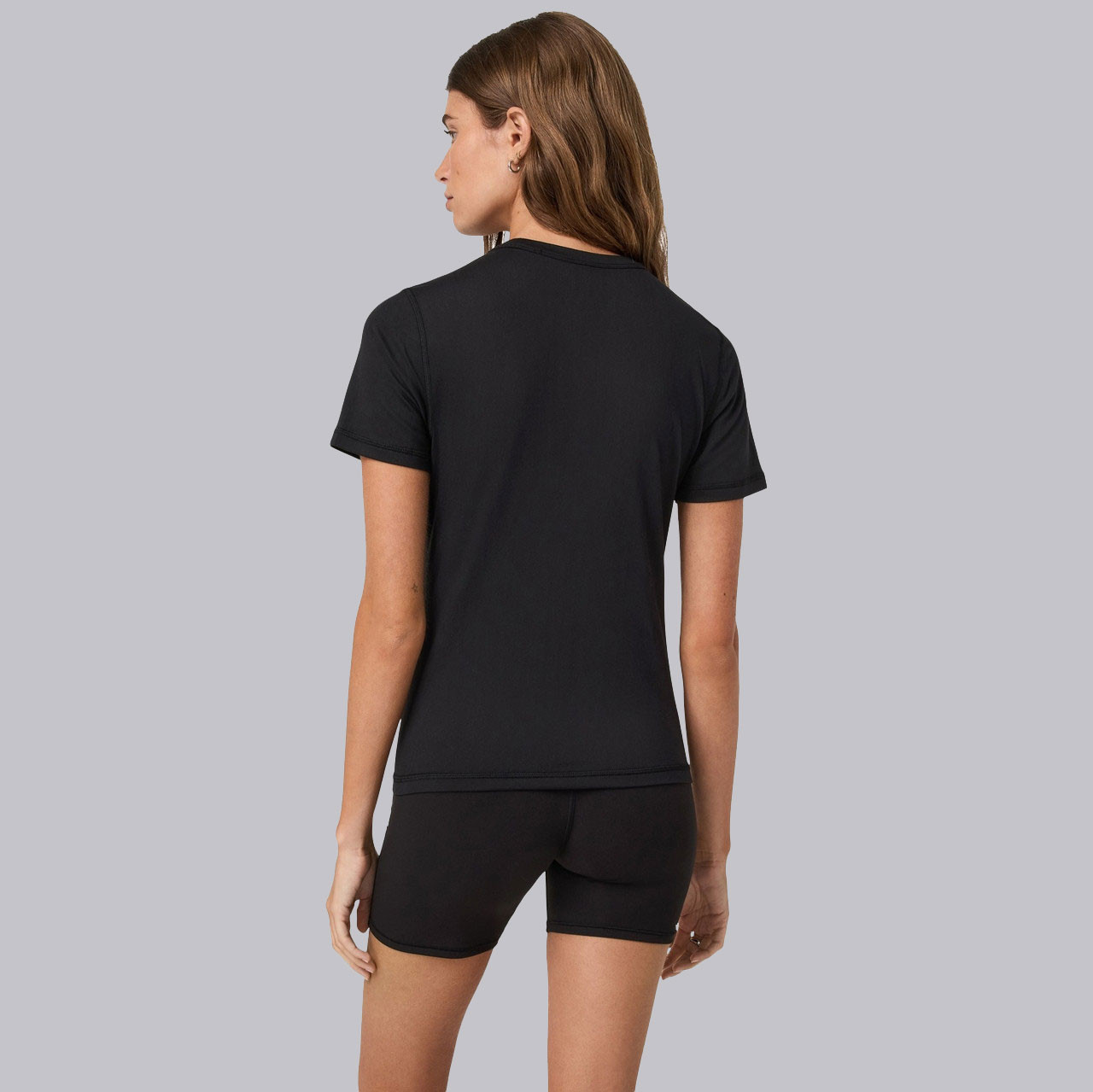 Vuori Women's Short Sleeve Lux Tee, woman wearing a black short sleeve performance t-shirt from the back.