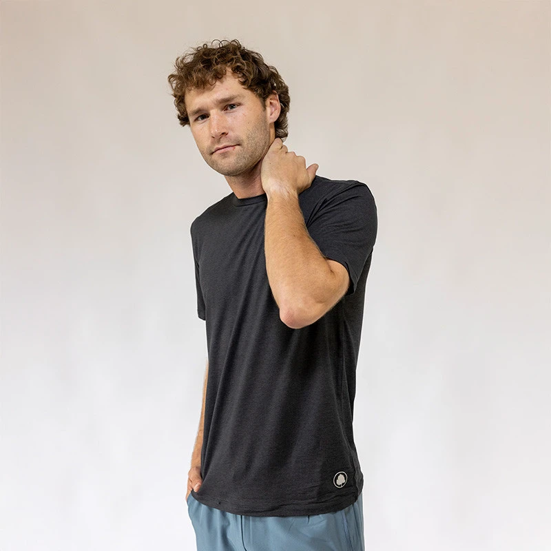 Alabama Outdoors Apparel AOA Men's Momentum Short Sleeve Tee, a man wearing a black athletic T-shirt with a small logo at the bottom, casual pose, plain light background.