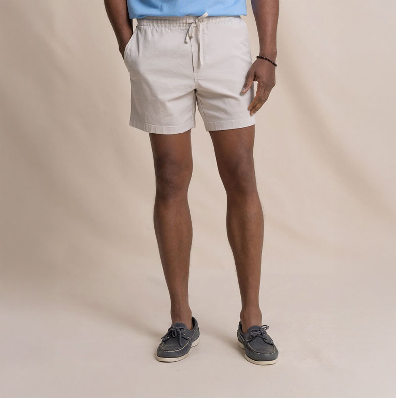 Southern Tide Men's Surf Rider Short, beige casual summer shorts with drawstring waist and side pockets, worn with boat shoes.