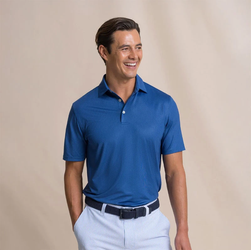 Southern Tide Men's Driver Seaside Geo Polo, a stylish blue men's polo shirt with Seaside Geo pattern, worn by a smiling male model.
