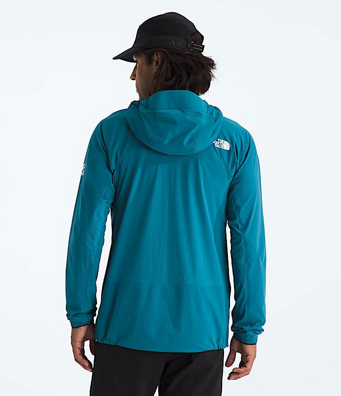 The North Face Men's Summit Off Width Jacket, back view of a man in a blue waterproof outdoor jacket with a hood, logo on shoulder, against a plain light background.