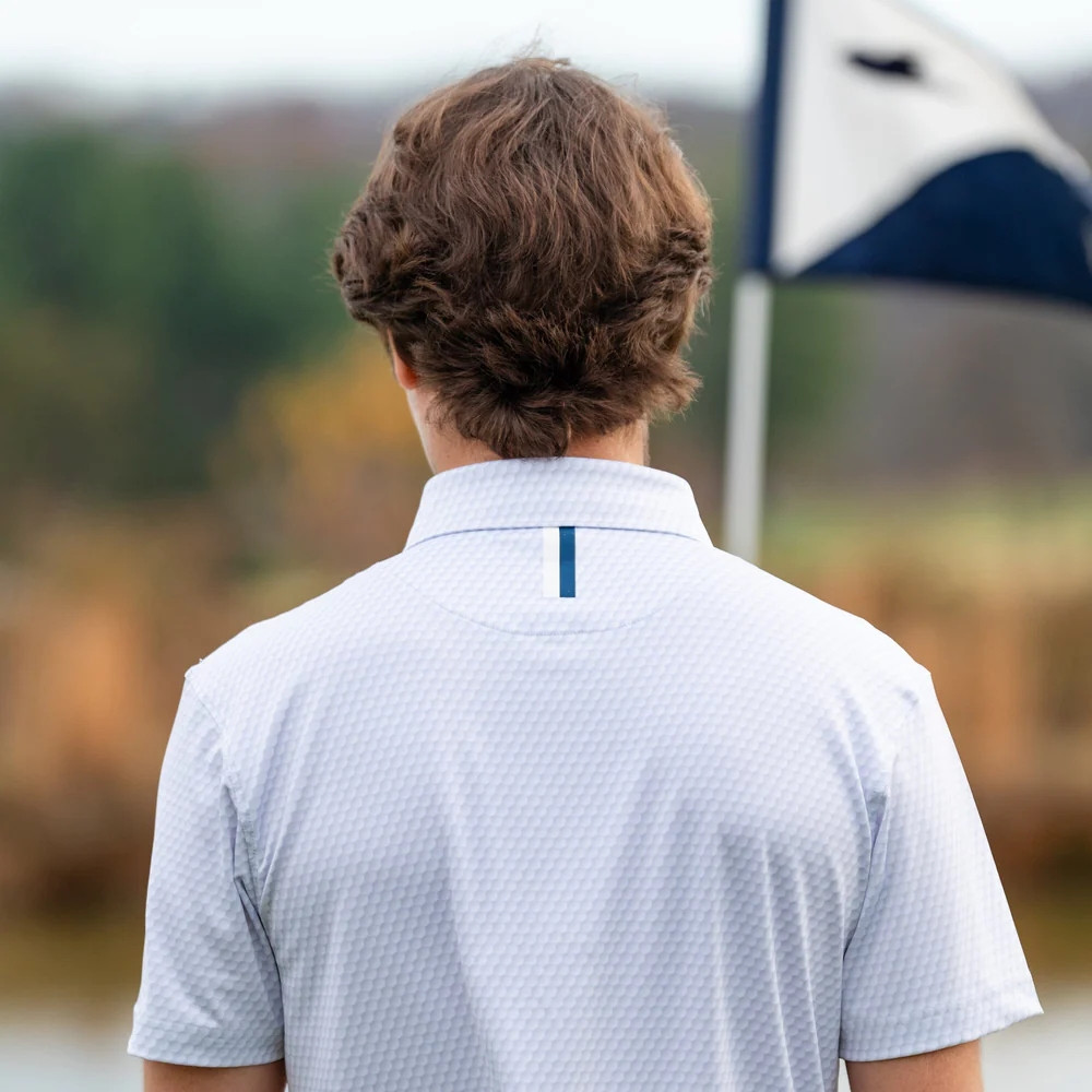 Rhoback Men's The Be The Ball Performance Polo, back view of a man wearing a white textured polo shirt outdoors.
