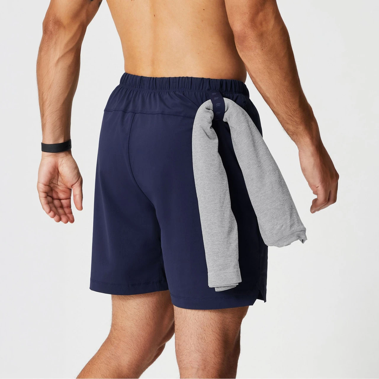 Fabletics Men's The One Short Lined - 7" Inseam, navy shorts with a grey hoodie tied around the waist.