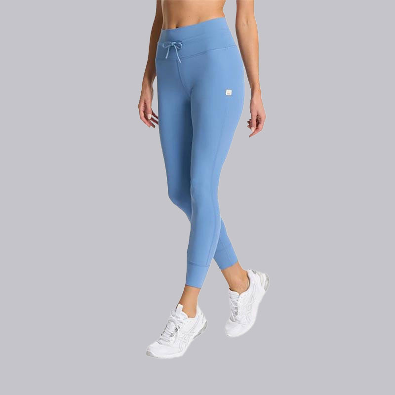 Vuori Women's Daily Leggings, light blue high-waisted leggings with a drawstring and small patch logo, paired with white sneakers.