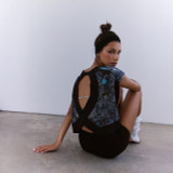 FP Movement Women's My Time Tee - Print, woman sitting on the floor wearing a stylish printed workout tee with an open back design and a black headband.