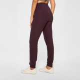 Fabletics Women's Cloud Jersey Jogger, purple lounge pants with a relaxed fit and comfortable elastic waistband, worn with white sneakers.