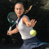Rhoback Women's Brooke Sleeveless Performance Polo, athletic woman hitting tennis ball with tennis racket outdoors.