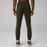 Fabletics Men's The One Jogger, image shows the back view of men's olive green joggers with elastic waistband, tapered legs, and zippered pockets.