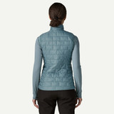 Patagonia Women's Nano Puff Vest, a blue quilted outdoor vest worn by a woman viewed from the back.