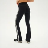 Splits59 Women's Raquel High Waist Double Stripe Supplex Flare 32 in, rear view of black high-waisted flare leggings with double white side stripes and 32-inch inseam, modeled with sneakers.