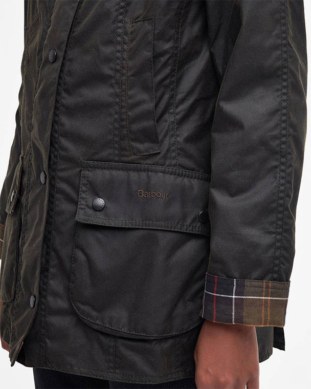 Barbour Women's Classic Beadnell Wax Jacket, close-up of the black waxed cotton jacket featuring a large pocket with flap and button, and a plaid-lined cuff detail.