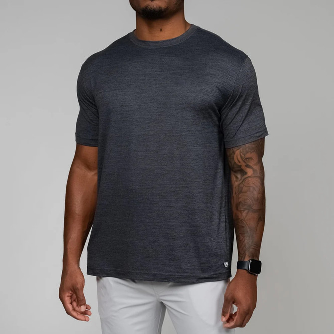 Rhoback Men's Tailwind Performance Tee, front view of a man wearing a dark gray athletic t-shirt with a subtle heather pattern and short sleeves, paired with white pants.