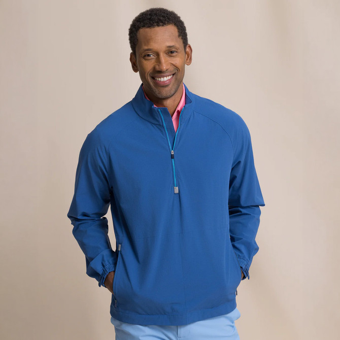Southern Tide Men's Seabreeze Perf Pullover, a man wearing a blue lightweight jacket with a quarter-zip front and a pink shirt underneath.