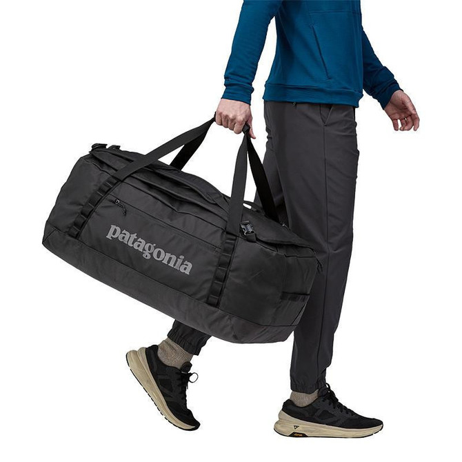Patagonia Black Hole Duffel 70L, black duffel bag being carried by a person in outdoor apparel.
