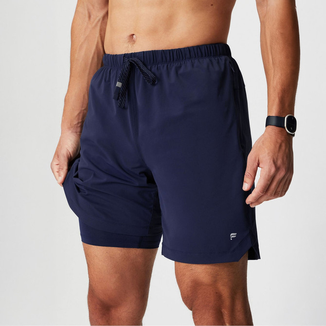 Fabletics Men's The One Short Lined - 7" Inseam, navy athletic shorts with an elastic waistband and drawstring, suitable for running or workouts.