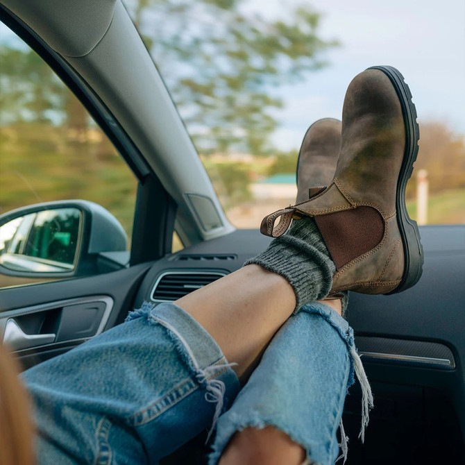 Blundstone Unisex Classic Chelsea Boot, rugged brown leather Chelsea boots worn by a person with jeans and gray socks relaxing in a car.