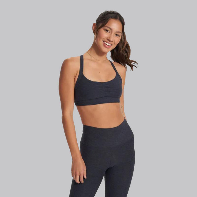 Vuori Women's Elevation Ruched Bra, stylish black sports bra with ruched detailing and adjustable straps worn by smiling woman