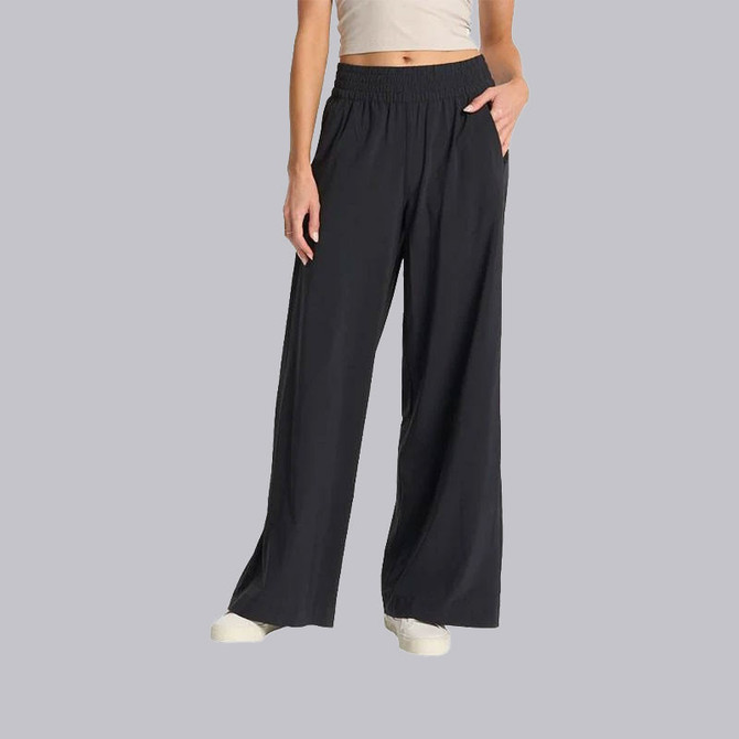 Vuori Women's Villa Wideleg, a pair of wide-leg black pants worn by a model with a beige top, in a casual and comfortable style.