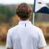 Rhoback Men's Short Sleeve Print Performance Polo, back view of a man wearing a white textured short sleeve polo shirt with a collar, outdoors with blurred background.