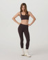 Vuori Women's AllTheForm Bra, a women wearing a black athletic crop top with matching high-waisted leggings and white sneakers with beige socks.
