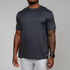 Rhoback Men's Tailwind Performance Tee, front view of a man wearing a dark gray athletic t-shirt with a subtle heather pattern and short sleeves, paired with white pants.