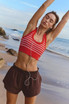 FP Movement Women's Go To Stripe Bra, red and white striped athletic crop top on woman stretching on beach.