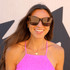 Knockaround Palomas Sunglasses, fashionable woman wearing black sunglasses with reflective lenses and a pink top, outdoors.