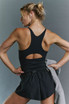 FP Movement Women's Carpe Diem Runsie, athletic woman in black sportswear showing back design with cutouts during workout.