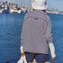 FP Movement Women's Restoration Yarn Dye Stripe Layer, image of a woman wearing a navy and white striped layer with a white hat near the water.