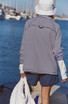 FP Movement Women's Restoration Yarn Dye Stripe Layer, model wearing striped jacket at a marina with boats in the background.