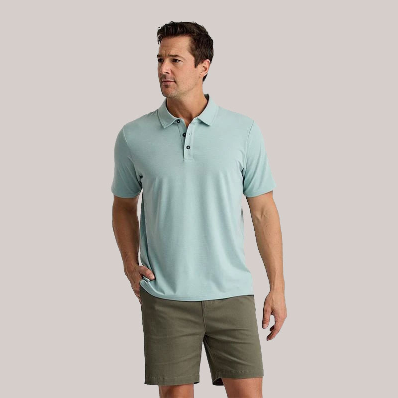 Free Fly Apparel Free Fly Men's Bamboo Flex Polo II, man wearing light blue bamboo blend polo shirt with short sleeves and button collar, paired with olive green shorts, casual summer outfit.