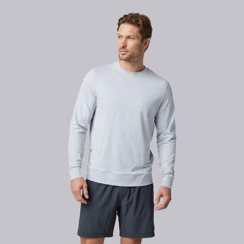 Vuori Men's Ponto Performance Crew, image of a man wearing a light gray performance crewneck sweatshirt with casual black shorts.