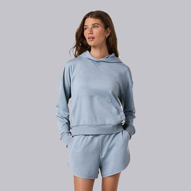 Vuori Women's Halo Modern Pullover Hoodie, a young woman wearing a light blue hoodie and matching shorts