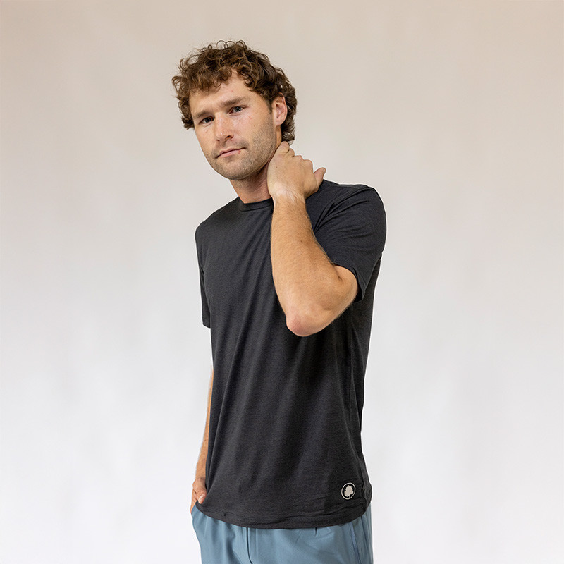 Alabama Outdoors Apparel AOA Men's Momentum Short Sleeve Tee, a man wearing a black athletic T-shirt with a small logo at the bottom, casual pose, plain light background.