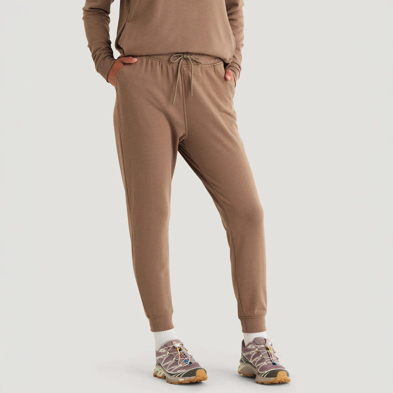 Free Fly Apparel Women's Bamboo Lightweight Fleece Jogger, taupe-colored casual joggers with elastic cuffs and drawstring waistband worn with hiking shoes.