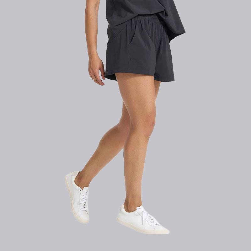 Vuori Women's Villa Short, black athletic shorts styled on a woman with white sneakers and a black top, casual and comfortable summer activewear.