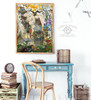 Framed woodland cottage fantasy artwork displayed above a desk in a cozy room