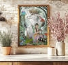 Fairy and hare fantasy artwork displayed in a warm wooden frame against a rustic white brick wall with flowers and greenery