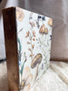 Back view of the framed Charming sculpture showcasing the decorative mushroom-patterned wallpaper and attached hanger for easy wall display.