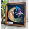 Dreamy is a handmade clay sculpture featuring a peaceful crescent moon face and whimsical mushroom, displayed in a handcrafted wooden frame with its own unique inspirational label.